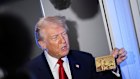 President Donald Trump spruiks his gold visa card to reporters in April. 