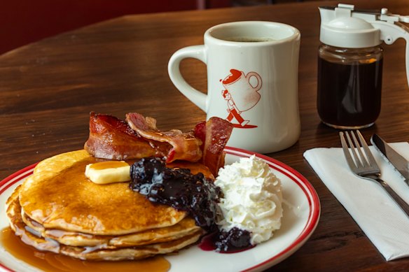 Pancake stack with whipped cream and bacon.