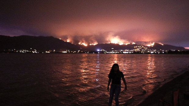 A girl wades through water while watching a wildfire burn in the Cleveland National Forest in Lake Elsinore, California.