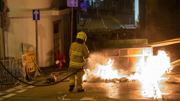 A firefighter extinguishes a fire set by demonstrators during a protest in Sheung Wan district of Hong Kong.