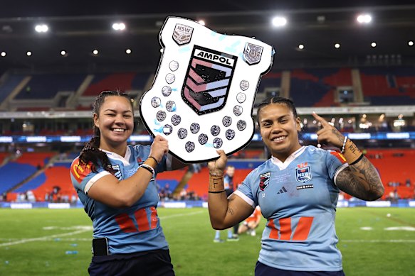 Kennedy Cherrington and Sarah Togatuki lift the Origin shield.