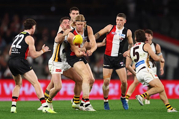 Tom De Koning dishes off a handball under pressure from Jai Newcombe.