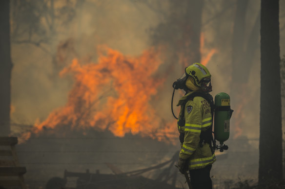 Firefighter Adam Brown protects properties along Glenthorne Road in South Taree on Sunday.