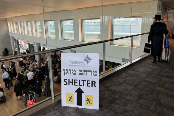 A “shelter” sign is displayed as people wait to board flights at Ben Gurion Airport near Tel Aviv on Monday.