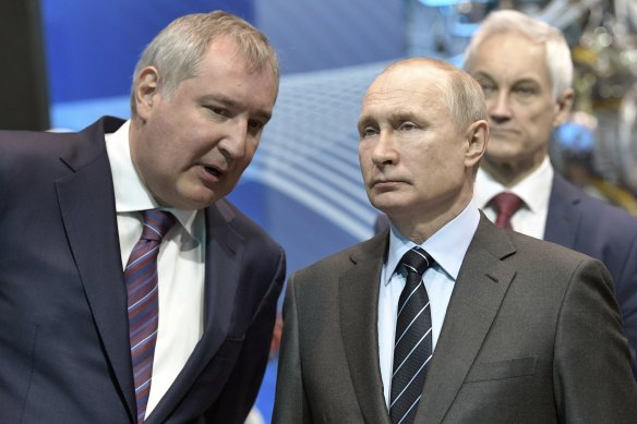 Başkan Vladimir Putin, sağda, Rus Roscosmos başkanı Dmitry Rogozin'in 2019'da konuşmasını dinliyor.
