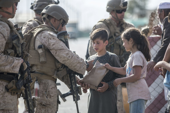 A US Marine hands food to children during an evacuation at Kabul airport.   