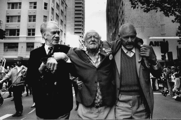 Tom Jones (left) and Henry McLachlan (right) help Norm Glover make it the end of the Anzac Day march in Sydney in 1991.