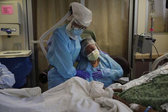 Romelia Navarro, right, is comforted by a nurse as she sits at the bedside of her husband, Antonio, who was dying of COVID-19 in California.