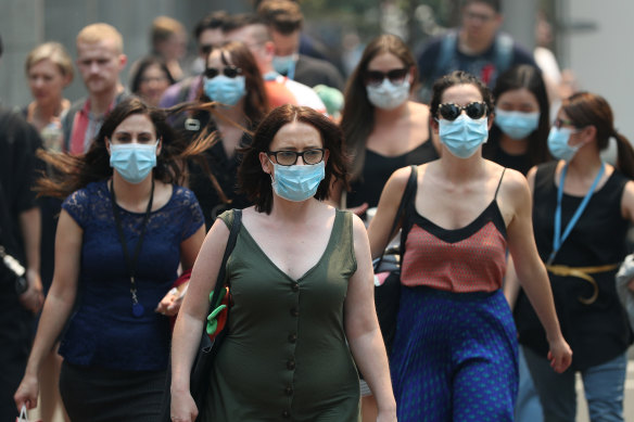 People are seen wearing face masks to protect from smoke haze as they cross a busy street in Sydney's CBD on Thursday.