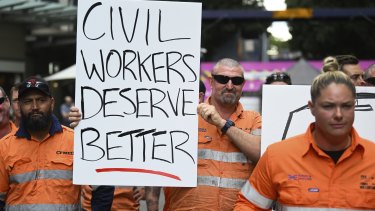 Striking CFMEU members, who work on the Albert St Cross River Rail construction site, hold signs outside the site in Brisbane, April 30, 2024.