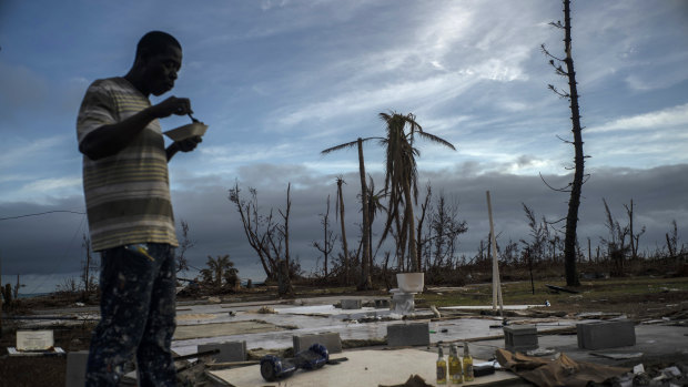 Jeffrey Roberts, 49, eats a plate of food while searching through the rubble of his relatives' destroyed home by Hurricane Dorian in Pelican Point.