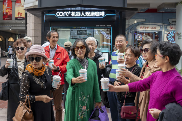 A group of customers at Cofe+ take pictures in front of the coffee-making robot booth on Nanjing Road, the busiest shopping street in Shanghai.