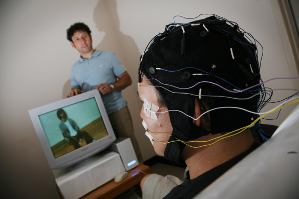 A researcher wears an electrode skull cap used to help heroin addicts. It  measures their reaction as they are shown a variety of images on a TV screen.