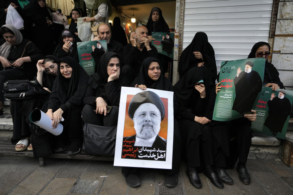 People hold up posters of Iranian President Ebrahim Raisi during a mourning ceremony for him in downtown Tehran, Iran.