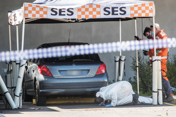 Homicide squad detectives and forensic officers examine a car at the Mernda police station.