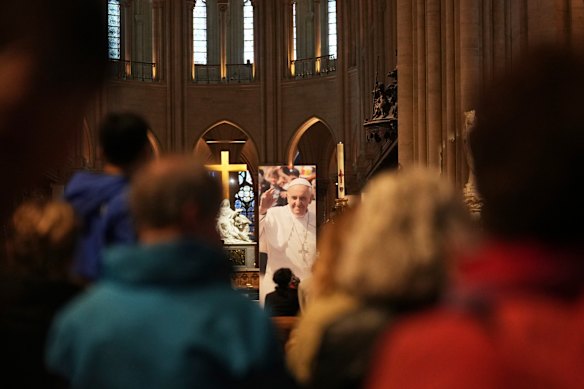People pray inside Notre-Dame cathedral where a poster of Pope Francis was installed after the pontiff’s death.