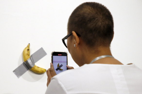 An art patron takes a picture of Italian artist Maurizio Cattelan’s piece, Comedian.