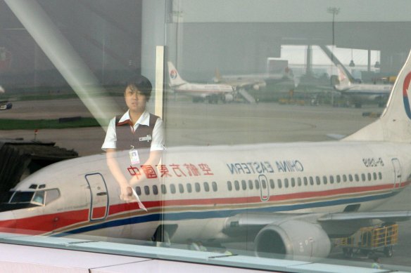 A ground staff is seen through a window on which the image of a China Eastern airplane in Beijing.