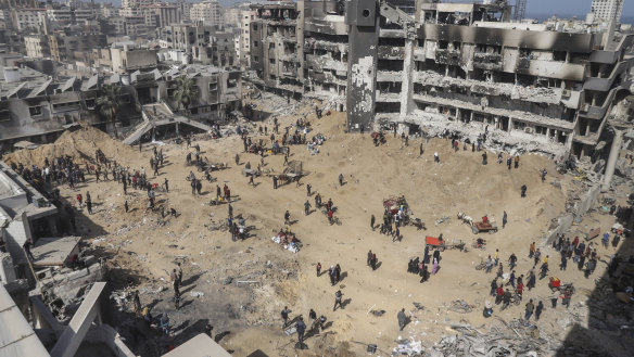 Palestinians walk through the destruction left by the Israeli air and ground offensive on the Gaza Strip near Shifa Hospital in Gaza City.