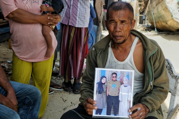 Syafudin M with a picture of his dead cousin, Laudi (centre).