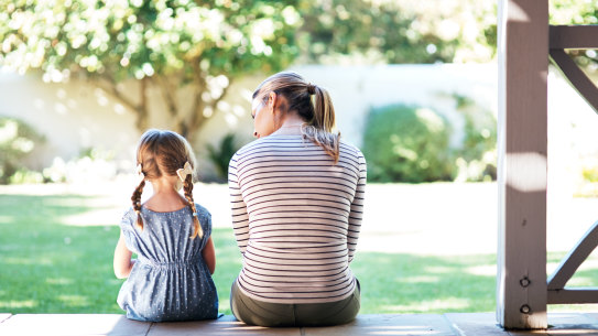 Mother talks to her daughter, on a deck.