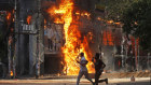 In Dhaka, a man films a burning shopping centre on his phone as he runs past. Protesters are demanding the resignation of Prime Minister Sheikh Hasina and her government.