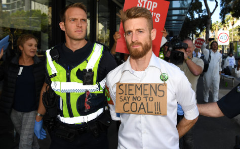 Victoria Police arrest a protester who glued his hand to a window during a protest at Siemens. 