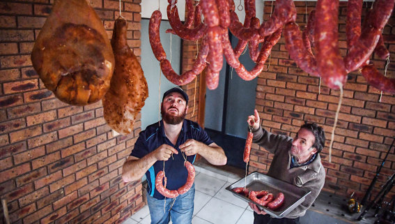 Proud papa: Frank Napoli, right, helps his son Steven, left, hang salami in a special curing alcove in Steven's Altona Meadows house. 