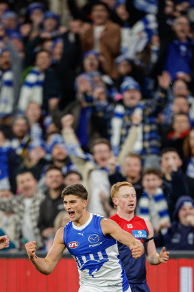 Harry Sheezel of the Kangaroos celebrates a goal as fans cheer him on.