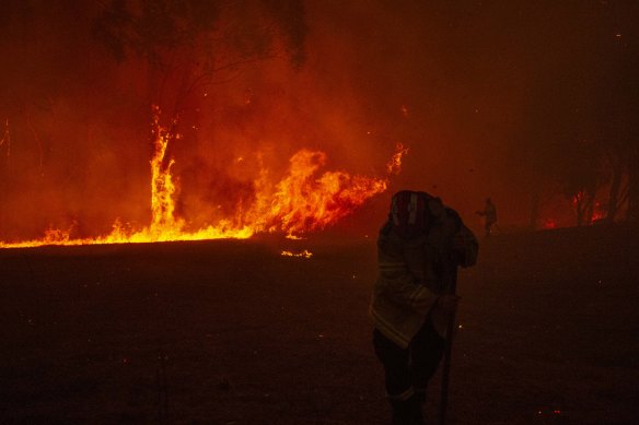 Firefighters undertake property protection as a bushfire impacts property in Mangrove Mountain on December 5.