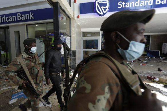Soldiers escort a man suspected of looting from inside a trashed shopping mall in Soweto, near Johannesburg.