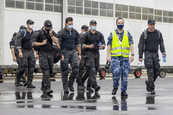 Australian Federal Police Special Operations members are escorted across the tarmac to a Royal Australian Air Force jet for their flight to the Solomon Islands on Thursday.