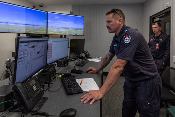Firefighter Adam Fulton checks screens inside the fire station’s windowless control room showing the airport outside. 