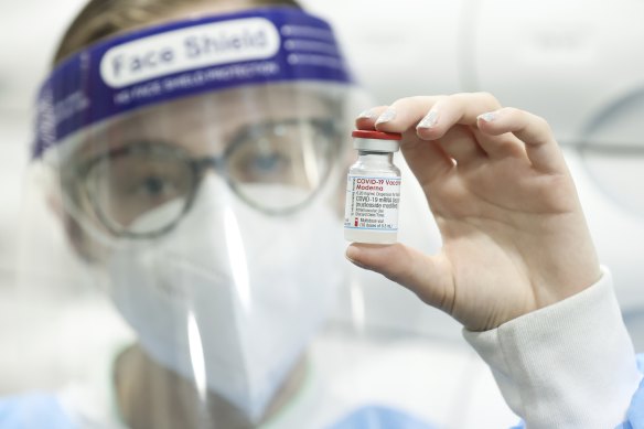 Pharmacist Chloe Langfield poses with a vial of the Moderna COVID-19 vaccine.