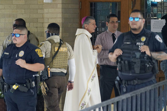 San Antonio Archbishop Gustavo Garcia-Siller waits as police create a barrier as guests arrive for the joint funeral service for Joe and Irma Garcia. 
