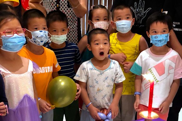 Children wearing face masks to protect against the coronavirus watch a performance at a shopping mall in Beijing.