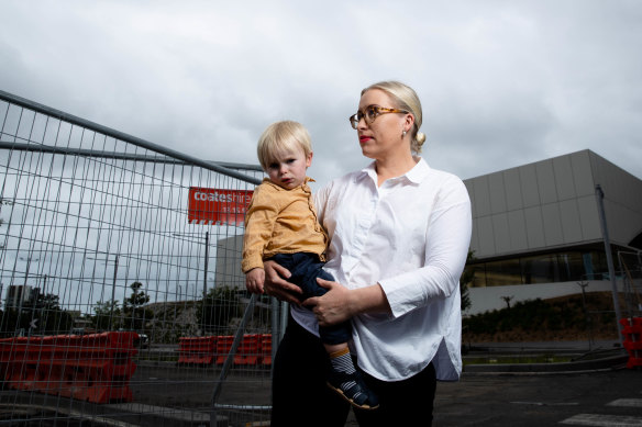 Zetland resident Angela Winkler and her two-year-old son Alfred in front of the fenced-off aquatic centre in Green Square.