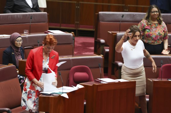 Lidia Thorpe appears to throw papers towards Pauline Hanson, with Fatima Payman (back left) seated behind them.