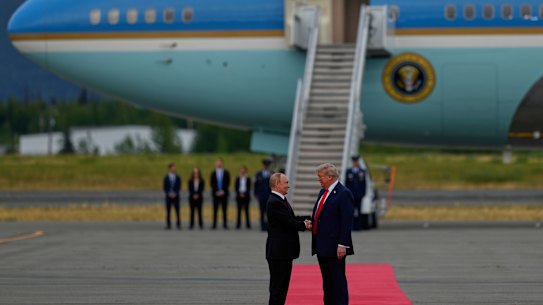 Donald Trump greets Vladimir Putin after he lands in Alaska.