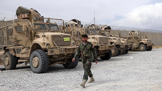 An Afghan army soldier walks past Mine Resistant Ambush Protected vehicles, MRAP, that were left after the American military left Bagram air base, in Parwan province north of Kabul, Afghanistan, Monday, July 5, 2021. 