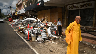 A Buddhist monk, part of a group visiting flood affected areas and do<em></em>nating mo<em></em>ney to victims, walks past a pile of debris in the Lismore central business district on Tuesday morning.