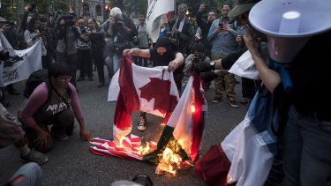 Protesters burn flags of the G7 nations while demonstrating against the summit on Thursday.
