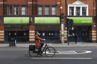 A woman rides a bicycle past a job centre in Shepherd’s Bush in London.