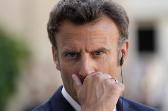 French President Emmanuel Macron listens to an interpreter at a press conference.