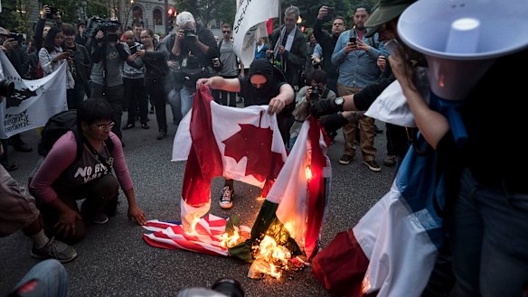Protesters burn flags of the G7 nations while demonstrating against the summit on Thursday.