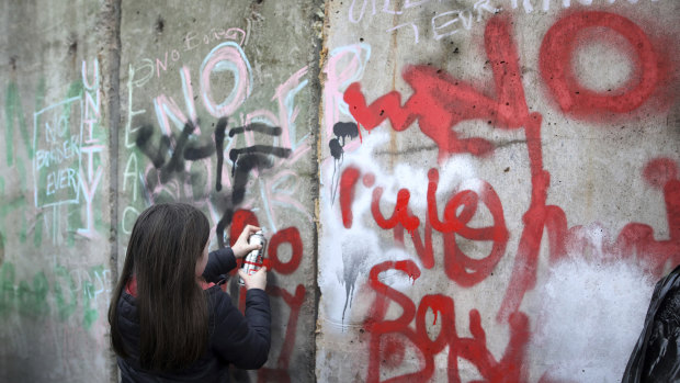 A young demonstrator spray paints on a 'mock' wall on the Northern Ireland-Ireland border near Newry.