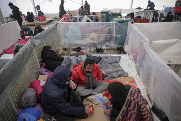 "Even animals are living better than us:" a Pakistani migrant pleads for shelter as men huddle together for warmth. 