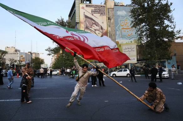 Demonstrators wave a huge Iranian flag in front of a building emblazoned with anti-Israeli messages in Tehran on Monday.
