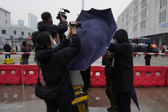 A plainclothes security person uses his umbrella to block journalists from filming after the World Health Organisation team arrive at the Baishazhou wholesale market on the third day of field visit in Wuhan in central China’s Hubei province on Sunday, January 31.