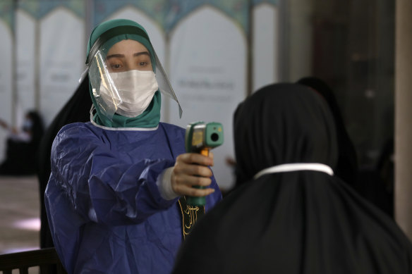 A volunteer checks the temperature of a worshipper as she enters the mosque of Tehran University.
